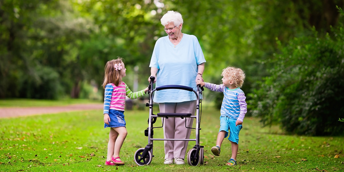 web3-happy-senior-lady-with-a-walker-holding-hands-of-little-boy-and-girl-grandmother-with-grand-children-enjoy-a-walk-in-summer-park-kids-supporting-disabled-grandparent-shutters