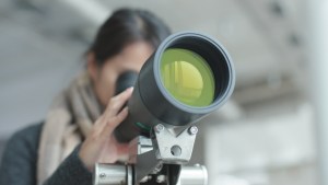 WOMAN LOOKING THROUGH TELESCOPE