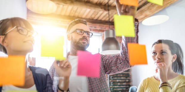 PEOPLE LOOKING AT POST-IT NOTES