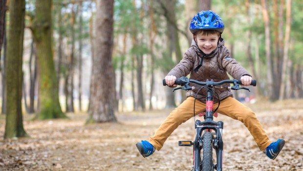Happy kid boy of 3 or 5 years having fun in autumn forest with a bicycle on beautiful fall day. Active child wearing bike helmet. Safety, sports, leisure with kids concept; wheels,bicycle,caucasian,helping,happy,enjoying,put,years,smile,