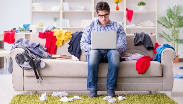 mężczyzna siedzi przy komputerze w zabałaganionym pokoju
