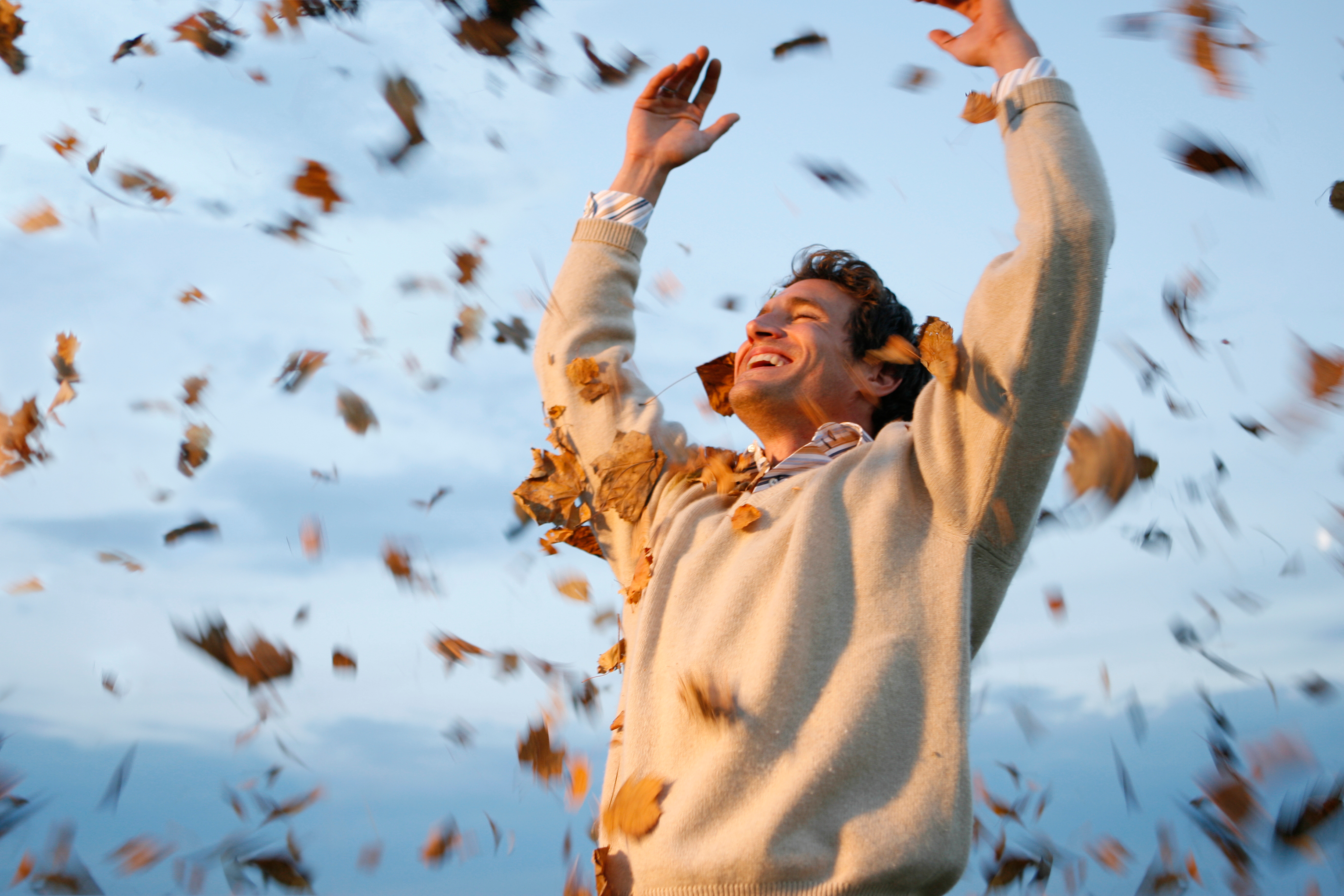 Man throwing autumn leaves in air