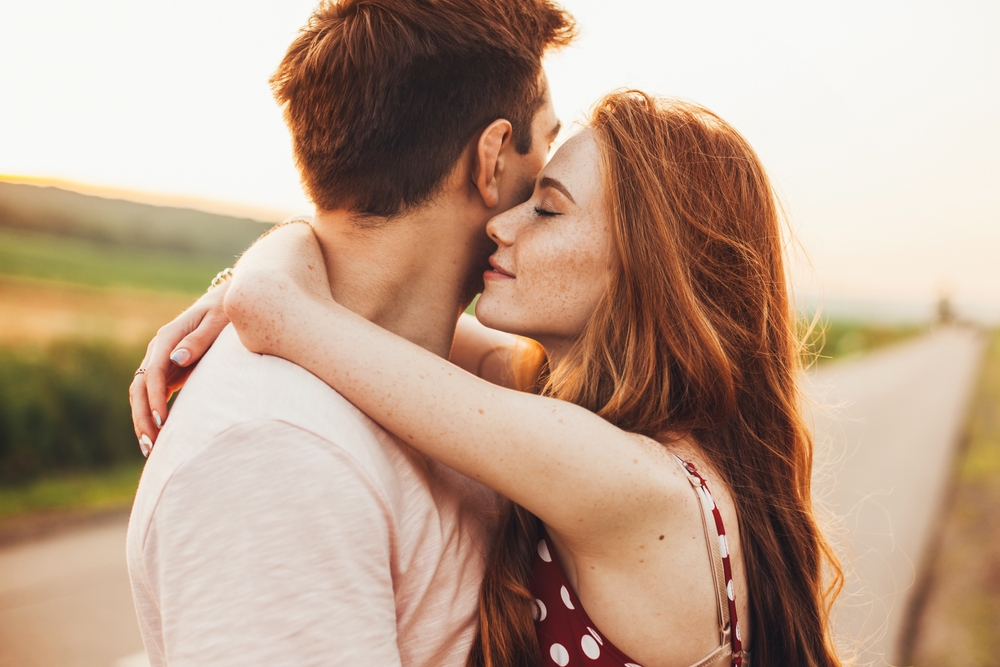 Close-up portrait of a caucasian young loving couple embracing while standing on a roadside. Couple embracing road travel. Sunset scene. | date,romance,couple,caucasian,happy,enjoying,spouse,smile,road,kissing,embracing,season,female,smiling,wife,dates,enjoyment,ginger,person,looking,autumn,adult,love,handsome,woman,weekend,cute,two,fall,romantic,street,walking,man,relationship,together,lovely,break,nature,valentine,portrait,lifestyle,afternoon,standing,sunlight,outdoors,authentic,hug,family,posing,walk