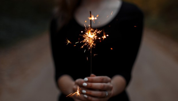 Women's hands hold a bright sparkler