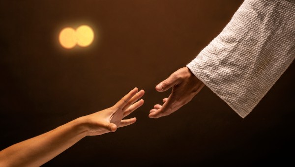 Jesus Christ reaching out to help those in need in a room lit with warm lights