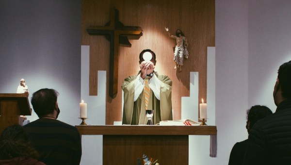 ksiądz podnosi Ciało Chrystusa przy ołtarzu