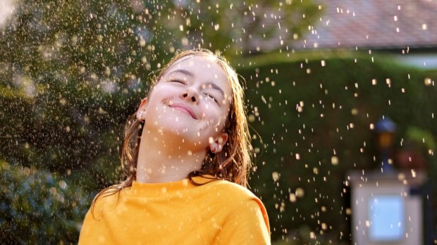 Happy-smiling-teenage-girl-enjoying-rain-and-sun-putting-her-face-under-water-drops-Shutterstock_1542223286.jpg