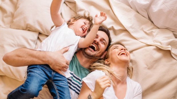 Happy family having fun in the bedroom while they lie on bed