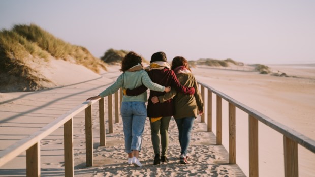 Three friends hugging each other while walking