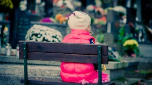 child praying in cemetery