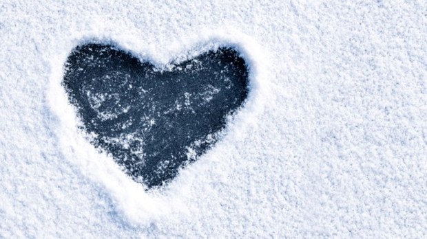 Heart shape love sign, drawn on a snow-covered ice on a winter lake