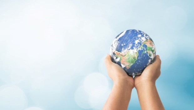 uman hands holding global over blurred blue nature background