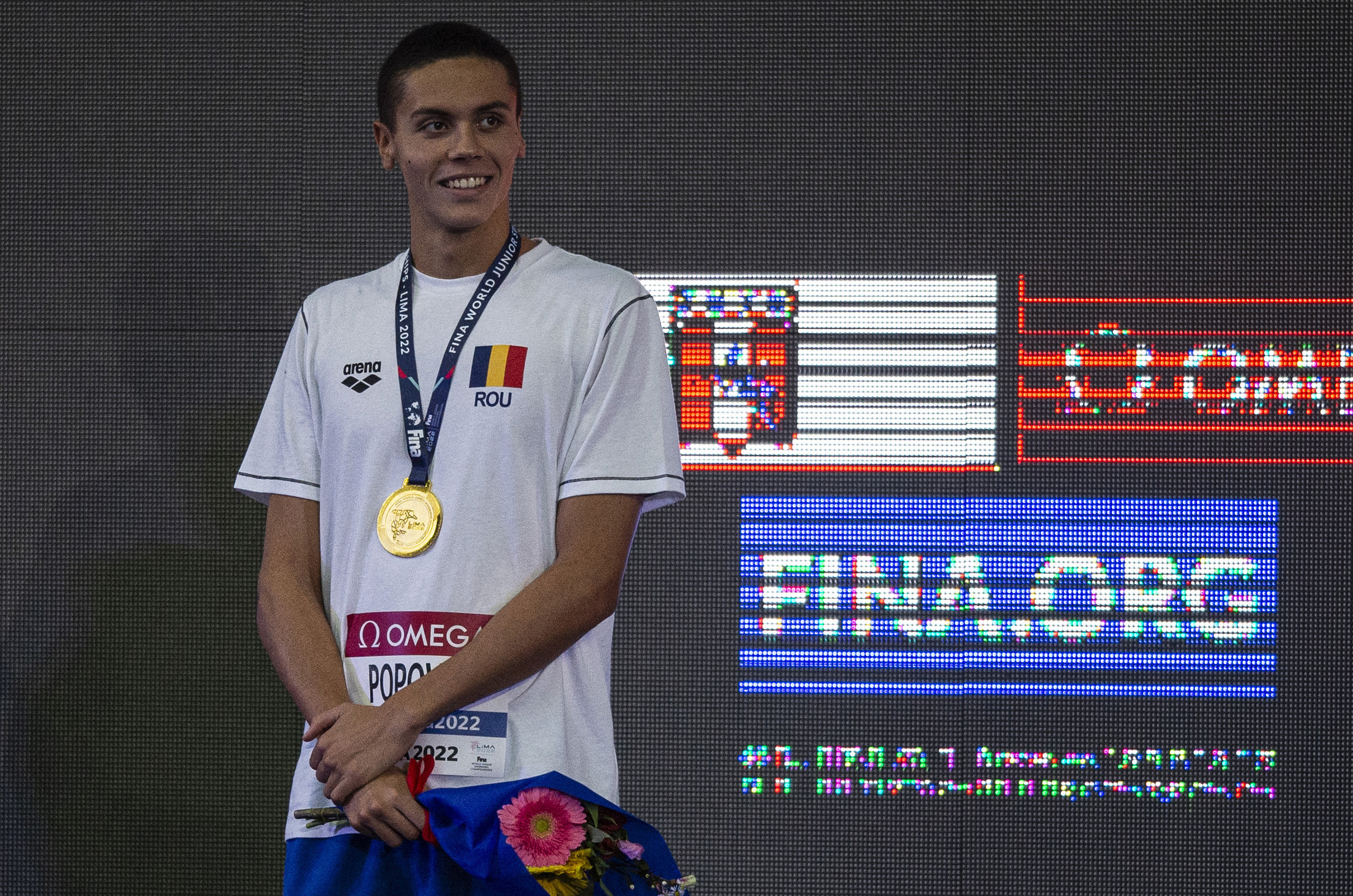 Romania's David Popovici celebrates in the podium of the Men's 100m Freestyle at the 8th FINA World Junior Swimming Championship in Lima