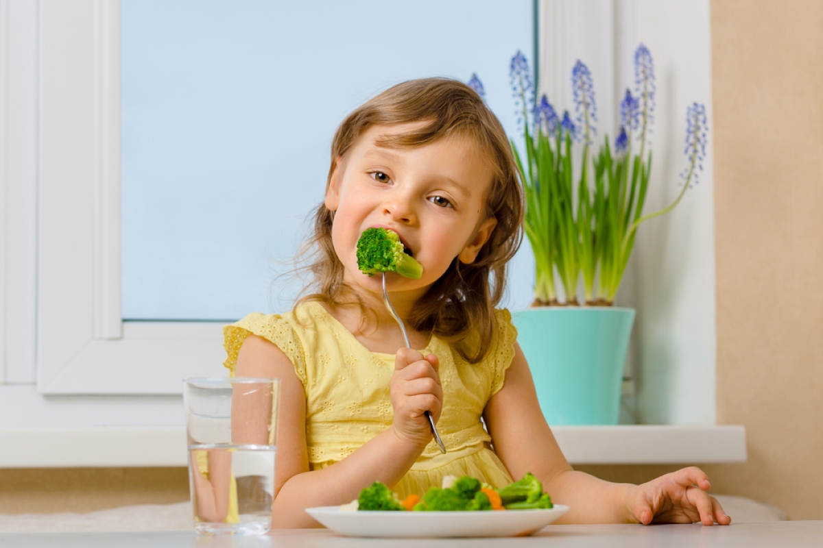 The child eats broccoli with an appetite