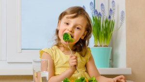 The child eats broccoli with an appetite
