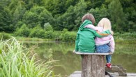 Two little children hug each other and look a the lake view
