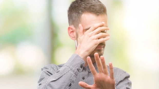 Young hipster man covering eyes with hands
