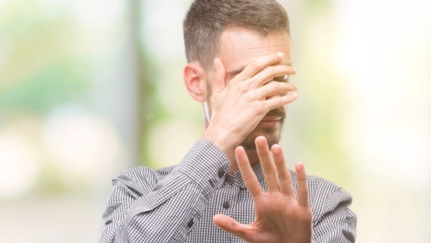 Young hipster man covering eyes with hands