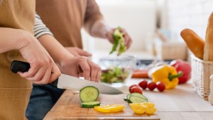 couple cutting vegetables in the kitchen together, preparing food meal at home