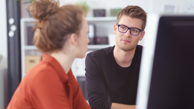 young businessman in a meeting listening to a female colleague