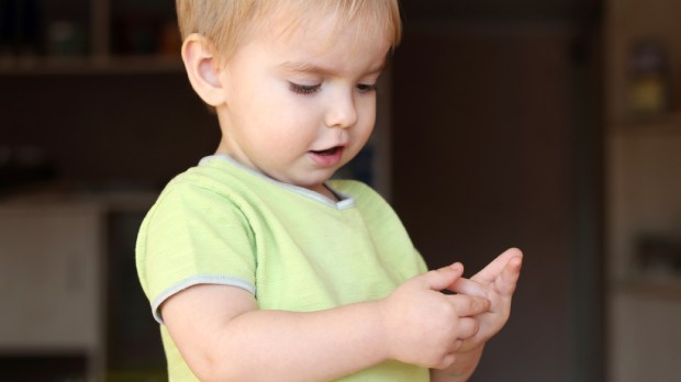 A toddler blond boy looking musingly and thoughtfully and counting his fingers