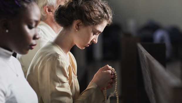 Young adult Catholic praying in church
