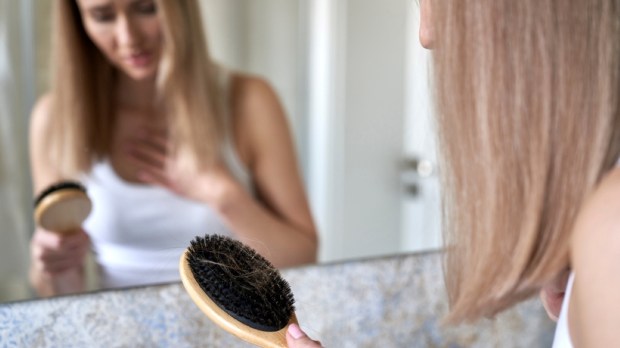 woman holding hairbrush with many hair on it
