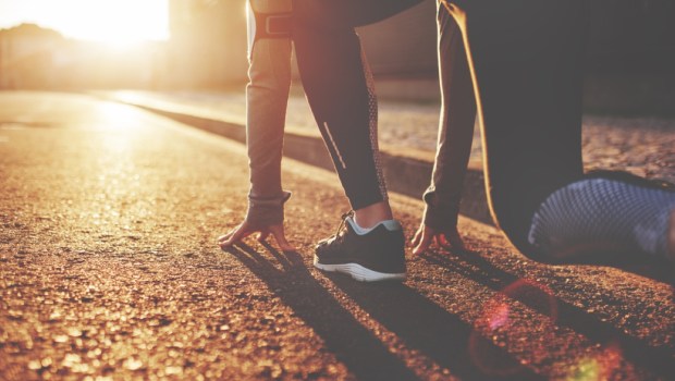 Athlete woman in running start pose on the city street