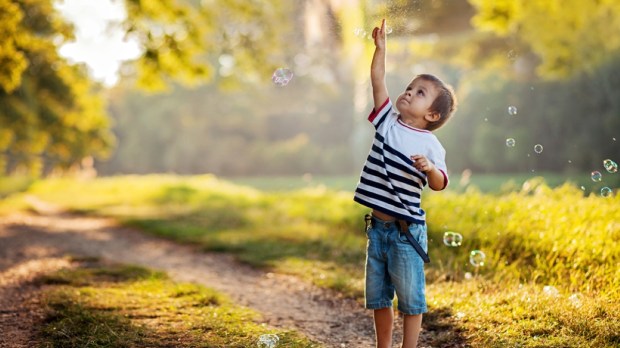 Boy in a park, chasing bubbles