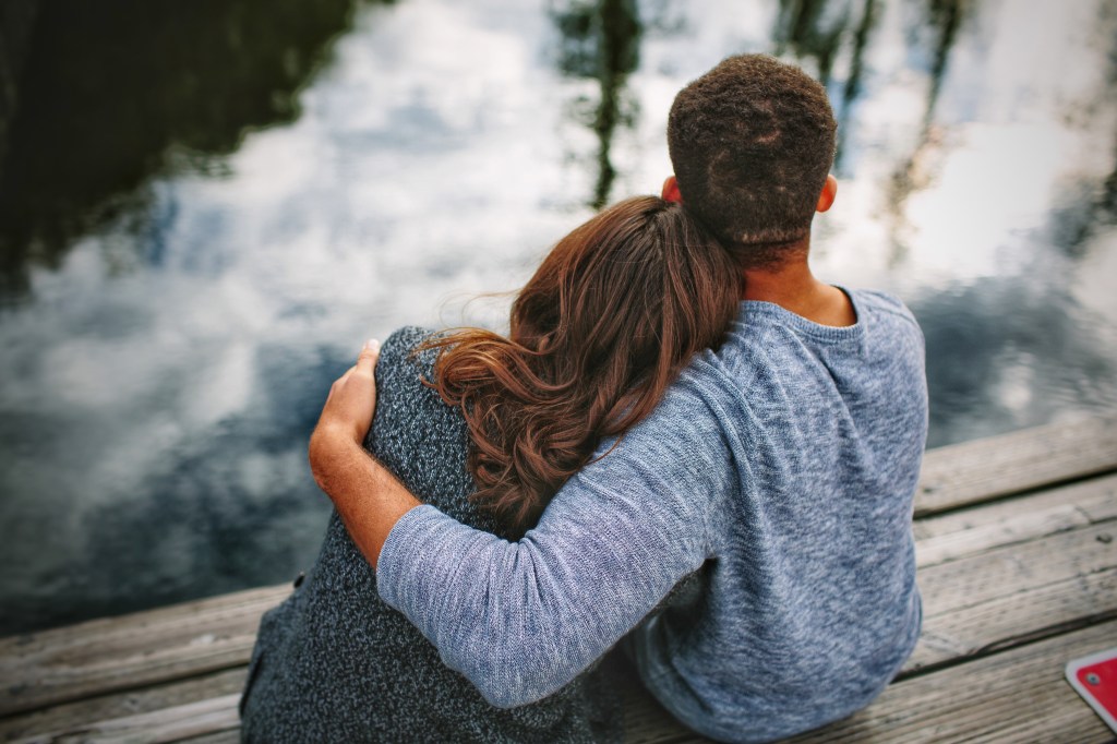 Couple embracing on dock, backs to camera