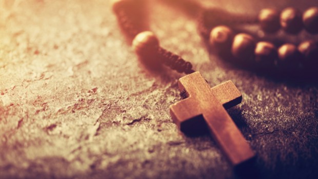Rosary with wooden cross on stone background