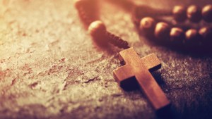 Rosary with wooden cross on stone background