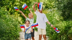 Three kids hold slovenian flags in Triglav National Park, Slovenia