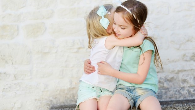 Two adorable little sisters laughing and hugging each other