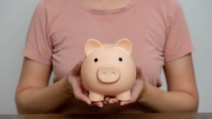 Woman saving money in a pink piggy bank