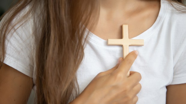 Kobieta trzyma krzyż przy swoim sercu
