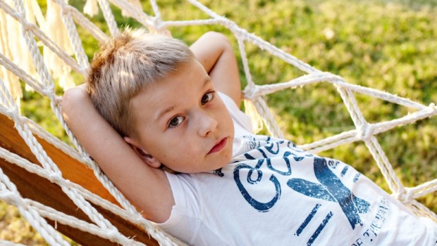 little boy is resting and dreaming in a hammock