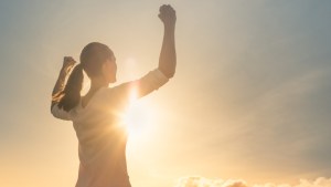 Strong woman, Winning, success , and life goals concept. Young woman with arms flexed facing the sunset.