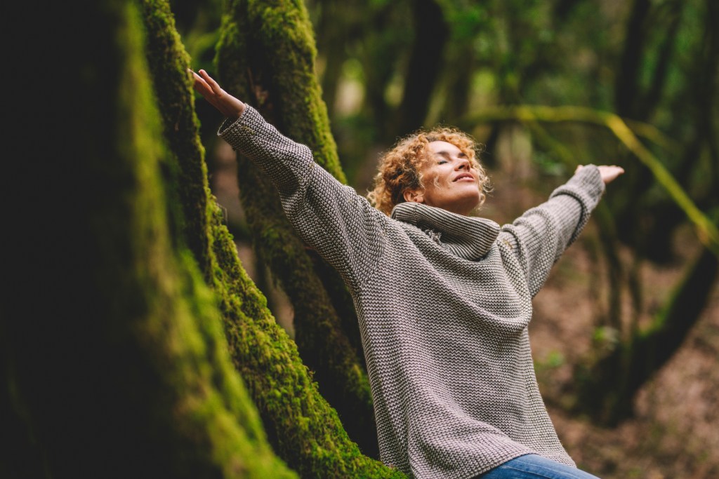 Una mujer feliz que disfruta del bosque verde y hermoso de la naturaleza