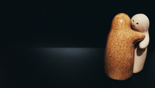 two ceramic dolls are hugging symbolizing two people who forgive each other