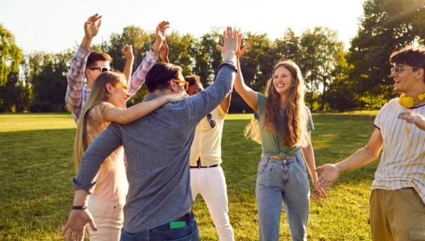 Group of happy young people have fun together while walking in park on warm summer evening