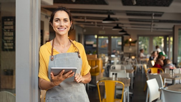 Portrait of happy woman standing at doorway of her store