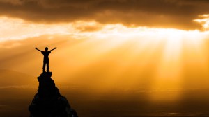 man on the top of a rock meeting sun