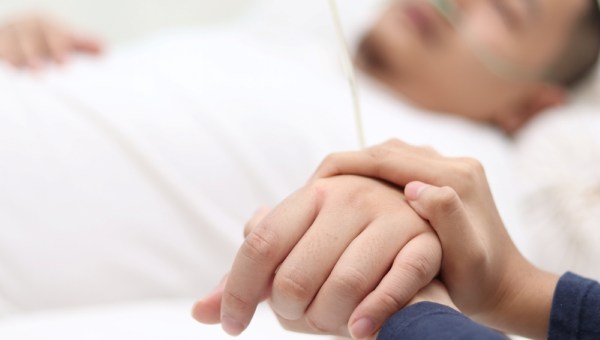 Close up of wife holds hand of her husband who is sick and sleep on bed in hospital - Photo-of-young