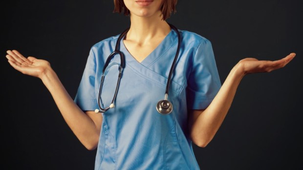 Nurse in a blue suit and with a stethoscope stands with outstretched arms.