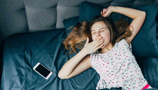 Nastolatka budzi się i ziewa w łóżku po przespanej nocy