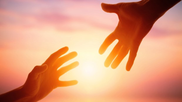 Giving a helping hand on the background of the dawn