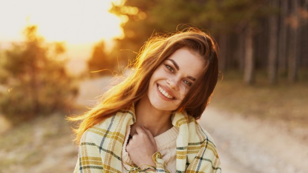 Happy woman with bread on her shoulders laughs front view and sunset in the background