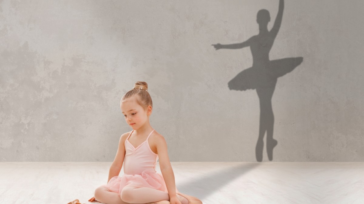 Little girl looking at pointe shoes, dreaming to become famous ballerina