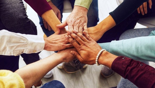 People of different ages and nationalities fold their hands on each other, symbolizing their unity and support. Team of people who are set up for productive work and a positive result. Close up.